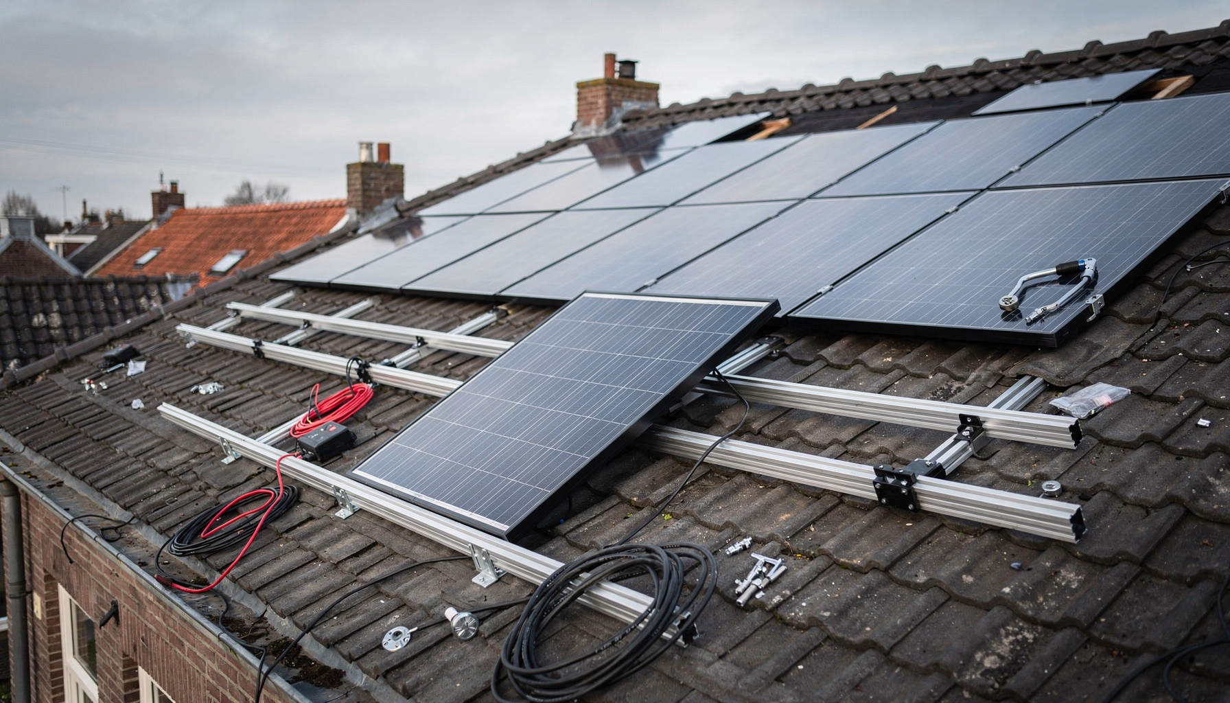 Halfgemonteerde zonnepanelen op een dakconstructie met gereedschap en bekabeling, zonder personen in beeld