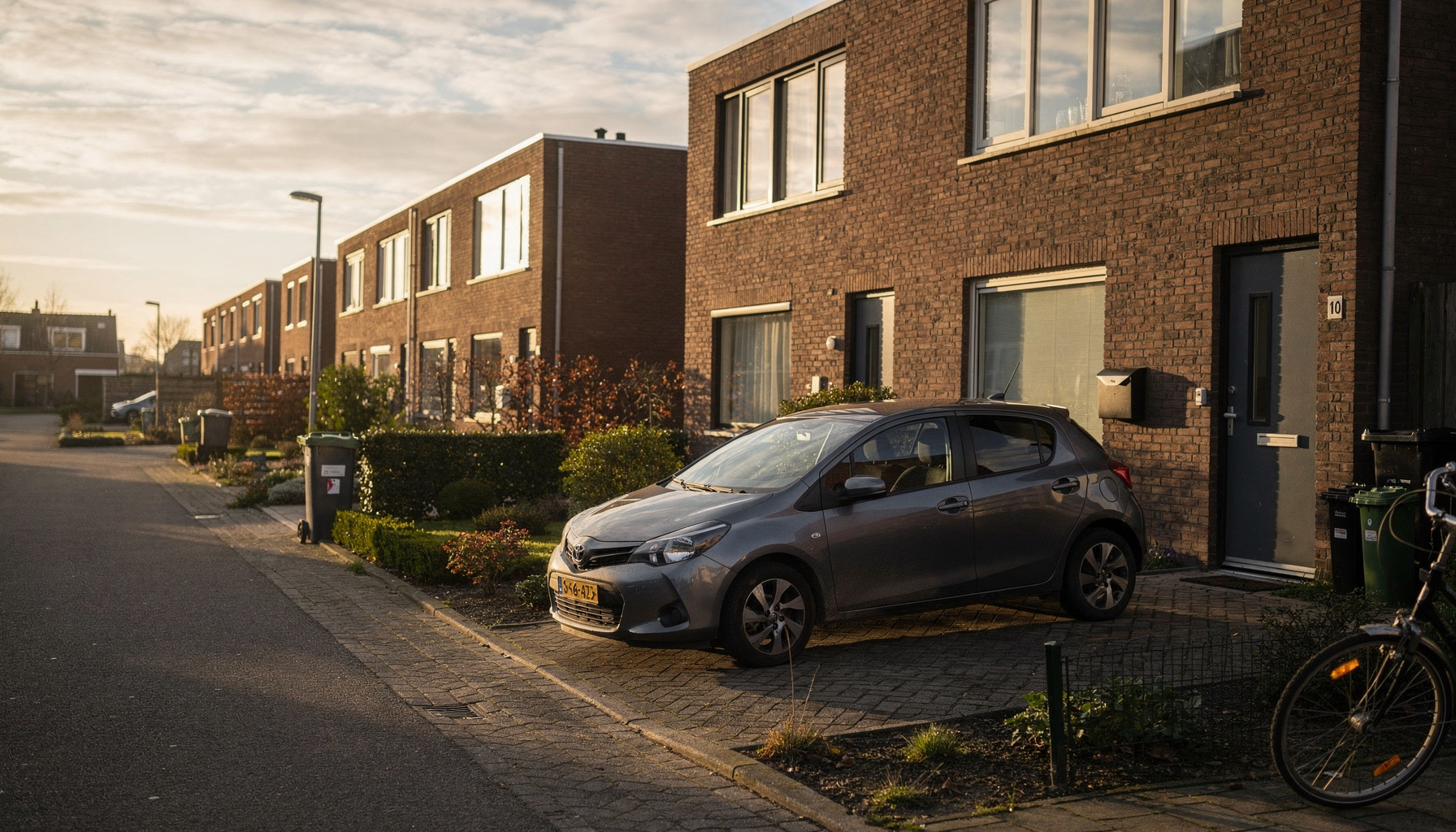 Compacte auto op een oprit voor een eengezinswoning in een rustige woonwijk in de ochtend