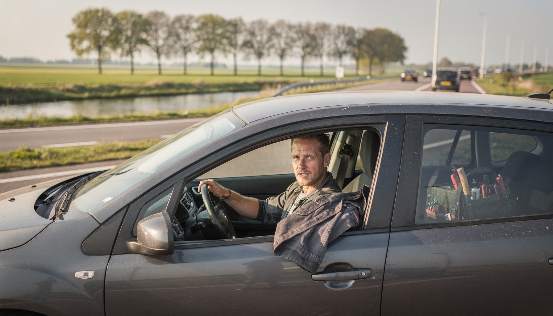 Zzp'er rijdt in een betaalbare hatchback over een Nederlandse landweg naar een klant
